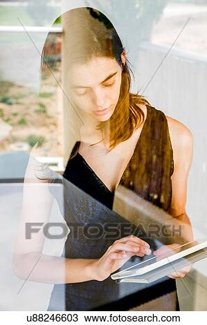 Young woman using digital tablet, photographed through glass View Large Photo Image Stock Image - Young woman using digital tablet, photographed through glass. Fotosearch