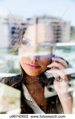 Young woman using smartphone, pensive expression, photographed through glass View Large Photo Image Stock Image - Young woman using smartphone, pensive expression, photographed through glass. Fotosearch