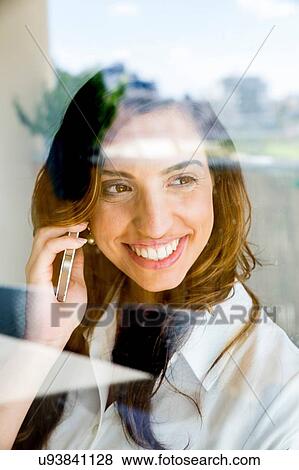 Young woman using smartphone, smiling, photographed through glass View Large Photo Image Stock Photo - Young woman using smartphone, smiling, photographed through glass. Fotosearch