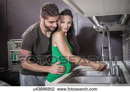 Young woman washing up whilst being embraced by boyfriend View Large Photo Image Stock Image - Young woman washing up whilst being embraced by boyfriend. Fotosearch