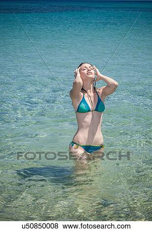 Young woman wearing bikini with hands in hair in sea, Cagliari, Sardinia, Italy View Large Photo Image Stock Photo - Young woman wearing bikini with hands in hair in sea, Cagliari, Sardinia, Italy. Fotosearch