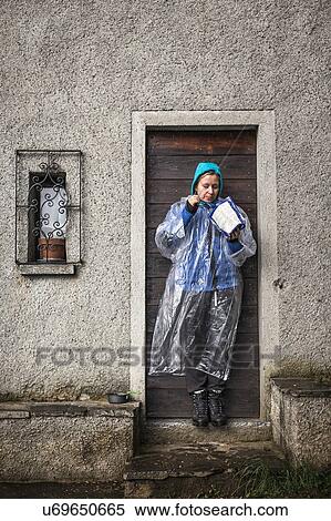 Young woman wearing rain mac standing in doorway, Lake Como, Italy View Large Photo Image Stock Photography - Young woman wearing rain mac standing in doorway, Lake Como, Italy. Fotosearch