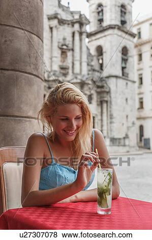 Stock Photo - Young woman with a Mojito cocktail in a restaurant on the Plaza de la Cathedral of Havana, Cuba. Fotosearch