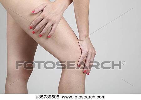 Stock Photography - Woman massages her painful knee. Fotosearch