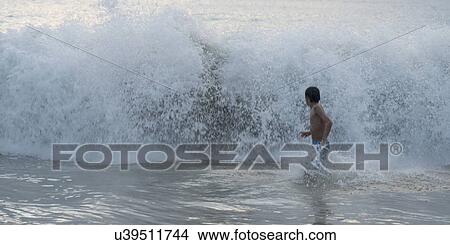 Picture - Boy running in waves on beach, Zihuatanejo, Guerrero, Mexico. Fotosearch