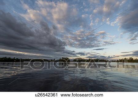 Stock Image - Clouds over a lake during sunset, Lake of the Woods, Ontario, Canada. Fotosearch