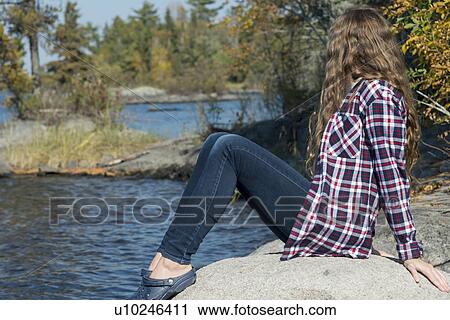 Girl sitting on rock at lakeside, Lake of the Woods, Ontario, Canada View Large Photo Image Stock Image - Girl sitting on rock at lakeside, Lake of the Woods, Ontario, Canada. Fotosearch