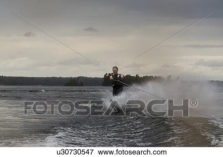 Stock Photo - Man waterskiing on a lake, Lake Of The Woods, Ontario, Canada. Fotosearch