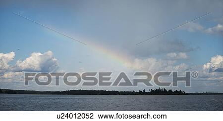 Stock Image - Rainbow over a lake, Lake of the Woods, Ontario, Canada. Fotosearch