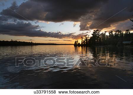 Silhouette of trees at lakeside during sunset, Lake Of The Woods, Ontario, Canada View Large Photo Image Stock Photo - Silhouette of trees at lakeside during sunset, Lake Of The Woods, Ontario, Canada. Fotosearch