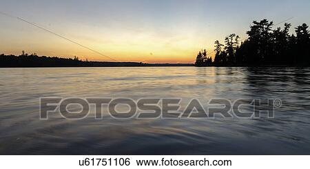 Stock Photograph - Silhouette of trees at the lakeside, Lake Of The Woods, Ontario, Canada. Fotosearch