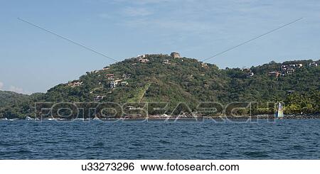 Stock Photograph - View of town on hillside along coastline, Zihuatanejo, Guerrero, Mexico. Fotosearch