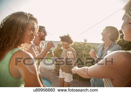 Adult friends drinking and dancing at poolside party View Large Photo Image Stock Image - Adult friends drinking and dancing at poolside party. Fotosearch