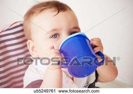 Stock Image - Baby boy drinking in baby chair. Fotosearch