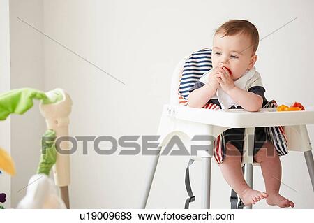 Baby boy feeding himself in baby chair View Large Photo Image Stock Image - Baby boy feeding himself in baby chair. Fotosearch