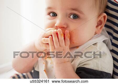 Baby boy feeding himself in baby chair View Large Photo Image Stock Image - Baby boy feeding himself in baby chair. Fotosearch