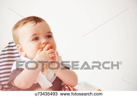 Baby boy feeding himself in baby chair View Large Photo Image Stock Image - Baby boy feeding himself in baby chair. Fotosearch