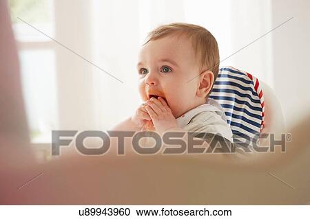 Baby boy feeding himself in baby chair View Large Photo Image Stock Image - Baby boy feeding himself in baby chair. Fotosearch