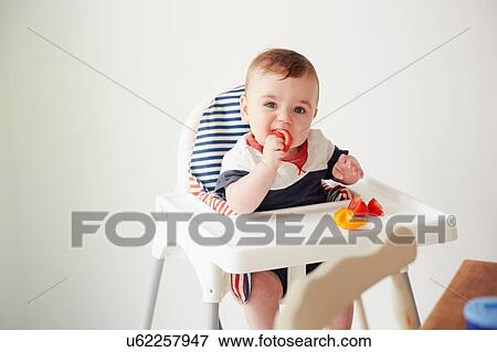 Baby boy feeding himself in baby chair View Large Photo Image Stock Photo - Baby boy feeding himself in baby chair. Fotosearch
