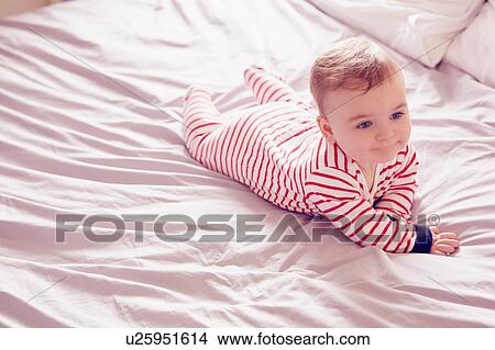 Picture - Baby boy lying on bed. Fotosearch