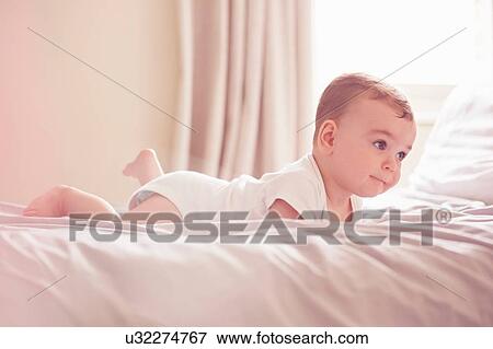 Baby boy lying on bed View Large Photo Image Stock Photo - Baby boy lying on bed. Fotosearch