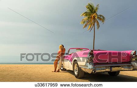 Stock Photo - Couple beside Convertible on beach. Fotosearch