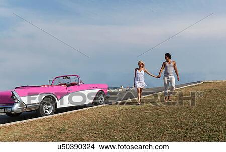 "Couple holding hands, Convertible in background" View Large Photo Image Picture - "Couple holding hands, Convertible in background". Fotosearch