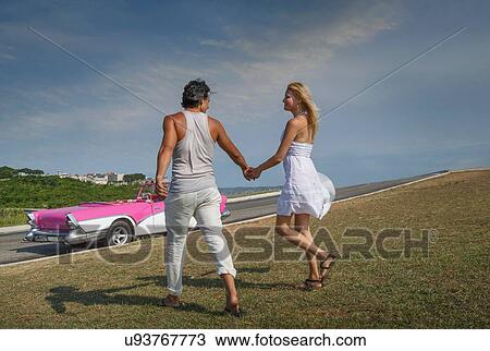 "Couple holding hands, Convertible in background" View Large Photo Image Stock Image - "Couple holding hands, Convertible in background". Fotosearch
