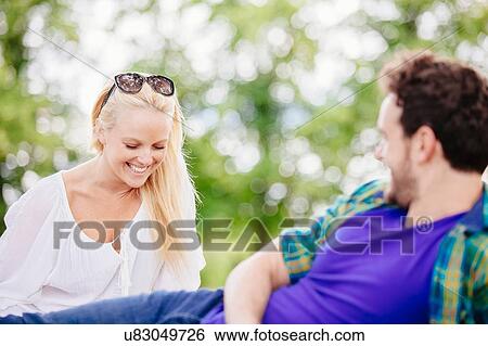 Stock Photograph - Couple relaxing outdoors talking and smiling. Fotosearch