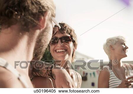 "Couple wearing sunglasses face to face, arm on shoulder smiling" View Large Photo Image Stock Photography - "Couple wearing sunglasses face to face, arm on shoulder smiling". Fotosearch