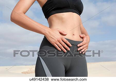 Stock Photo - Cropped shot of mid adult woman exercising on beach. Fotosearch
