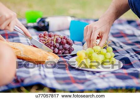Cropped view of couples hands reaching for grapes on picnic blanket View Large Photo Image Stock Photo - Cropped view of couples hands reaching for grapes on picnic blanket. Fotosearch