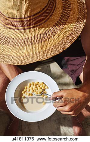 Cropped view of young man wearing sunhat eating breakfast cereal View Large Photo Image Stock Photograph - Cropped view of young man wearing sunhat eating breakfast cereal. Fotosearch