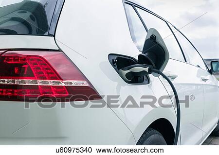 Stock Image - Electric car being charged at charging station. Fotosearch
