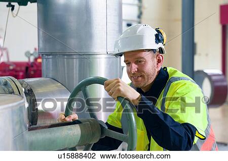 Stock Image - Engineer adjusting valves in geothermal power station. Fotosearch