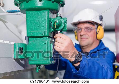 Stock Image - Engineer checking industrial equipment at geothermal power station. Fotosearch