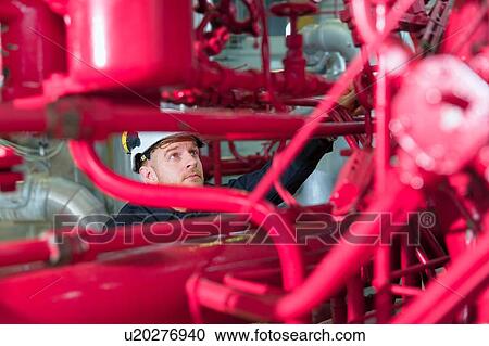 Stock Image - Engineer inspecting equipment in geothermal power station. Fotosearch