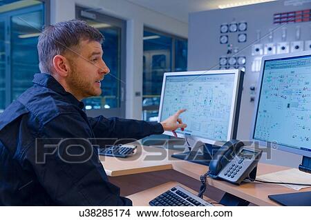 Picture - Engineer pointing at computer in control room at geothermal power station. Fotosearch