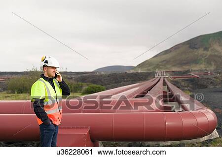 Stock Image - "Engineer talking on smartphone at geothermal power station, Reykjanes, Iceland". Fotosearch