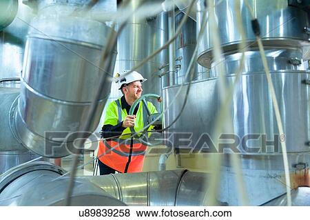 Stock Photo - Engineer turning wheel in geothermal power station. Fotosearch