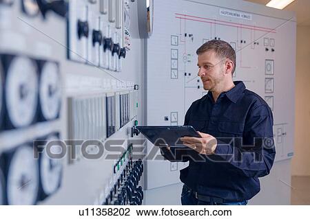 Stock Image - Engineer updating control panel using digital tablet at geothermal power station. Fotosearch