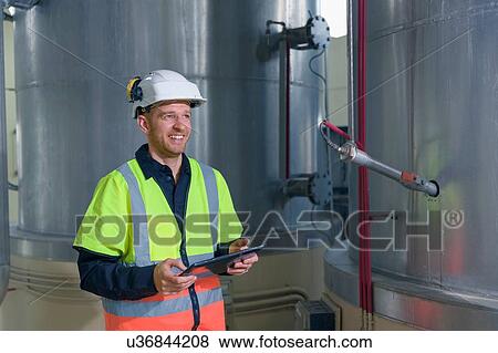 Engineer using digital tablet by storage tanks in geothermal power station View Large Photo Image Stock Photo - Engineer using digital tablet by storage tanks in geothermal power station. Fotosearch