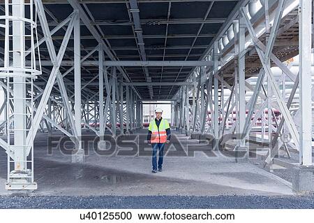 Stock Image - Engineer walking through warehouse space at geothermal power station. Fotosearch