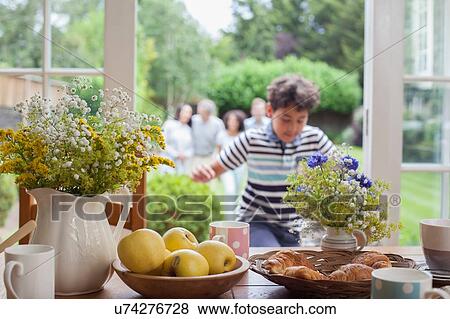 Stock Photo - Family coming in for breakfast after walk in garden. Fotosearch