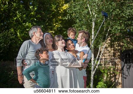 Stock Image - "Family in the garden taking a self portrait, using a selfie stick". Fotosearch