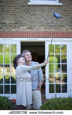 "Father and grown daughter in garden taking a self portrait, using a selfie stick" View Large Photo Image Stock Photo - "Father and grown daughter in garden taking a self portrait, using a selfie stick". Fotosearch