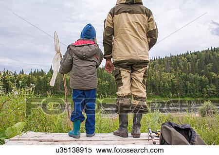 Stock Photography - "Father and son standing on jetty with fishing equipment, rear view". Fotosearch