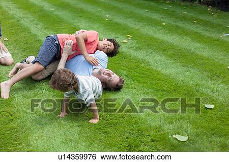 Father and two sons fooling around in garden View Large Photo Image Stock Photograph - Father and two sons fooling around in garden. Fotosearch