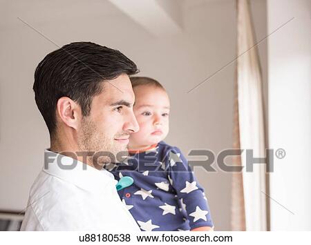 Stock Photo - Father and young son looking out of window. Fotosearch