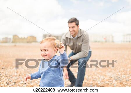 Father and young son playing on pebble beach View Large Photo Image Stock Photo - Father and young son playing on pebble beach. Fotosearch